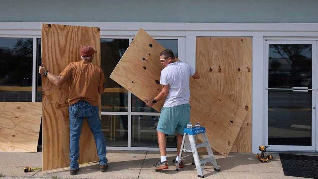 Two men in Gulf Breeze, Florida board up the windows of their shop as Hurricane Isaias approaches.