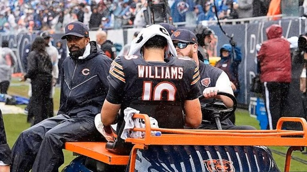 Caleb Williams has a towel over his head and sits on a buggy as he's driven off the field injured playing for the Chicago Bears